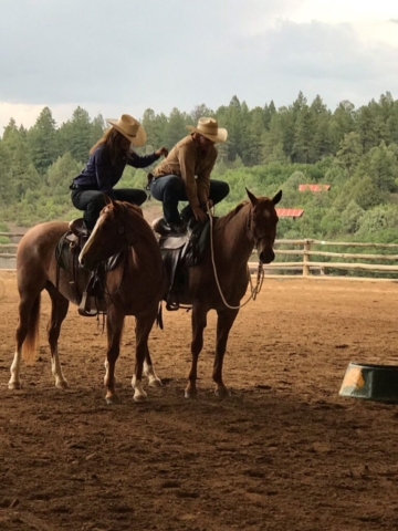 Two people crouching on their horses' saddles