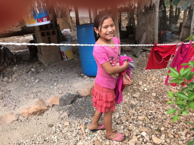 Mayan girl hanging laundry, smiling
