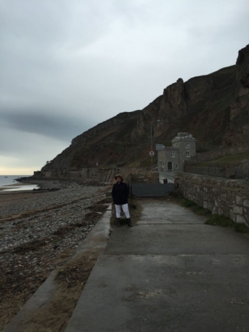 Ruth standing near small castle on the Irish Sea, North Wales