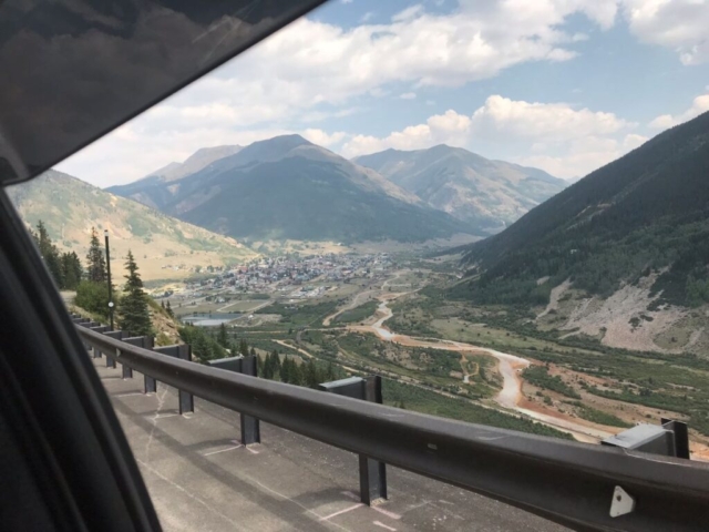 Photo from car of guardrails, with town and mountains ahead